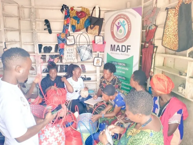 Women hold crafts during a skills session in front of a Maru Foundation banner