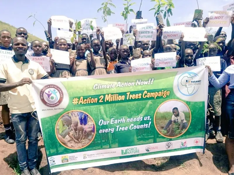 Participants hold up an Action 2 Million Trees Campaign banner reading Our Earth needs us, every tree counts