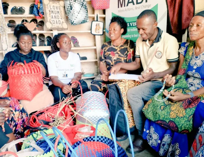 Women and a facilitator sit among handmade baskets and crafts during a livelihoods session