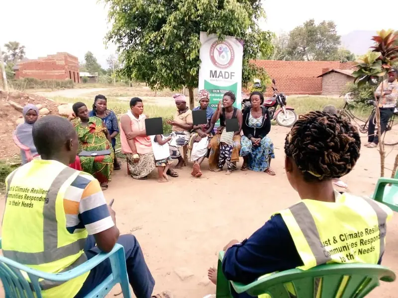 Farmers sit in a circle for an outdoor agribusiness meeting