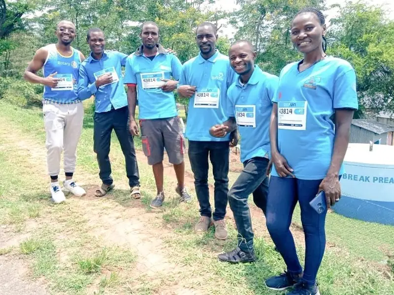 Young volunteers in matching blue shirts stand in a line outdoors