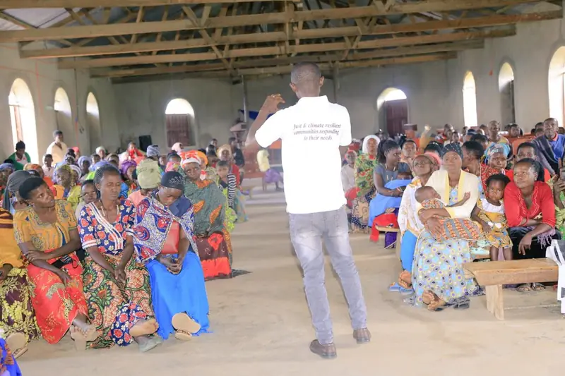 A facilitator speaks to a large audience during an advocacy meeting in a hall