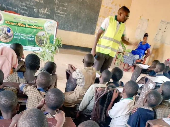 A volunteer talks to young children in a classroom during a tree campaign visit