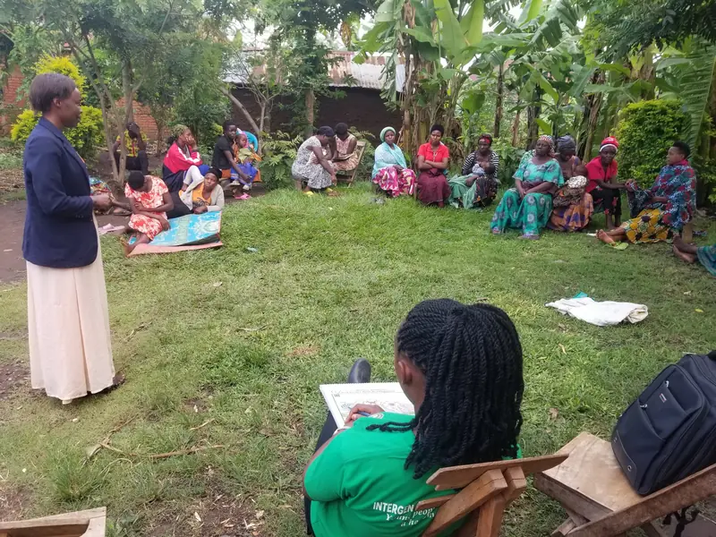 Community members sit in a large circle on the grass for a training session