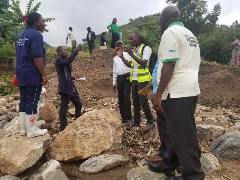 Team members inspect a riverbank damaged by flooding