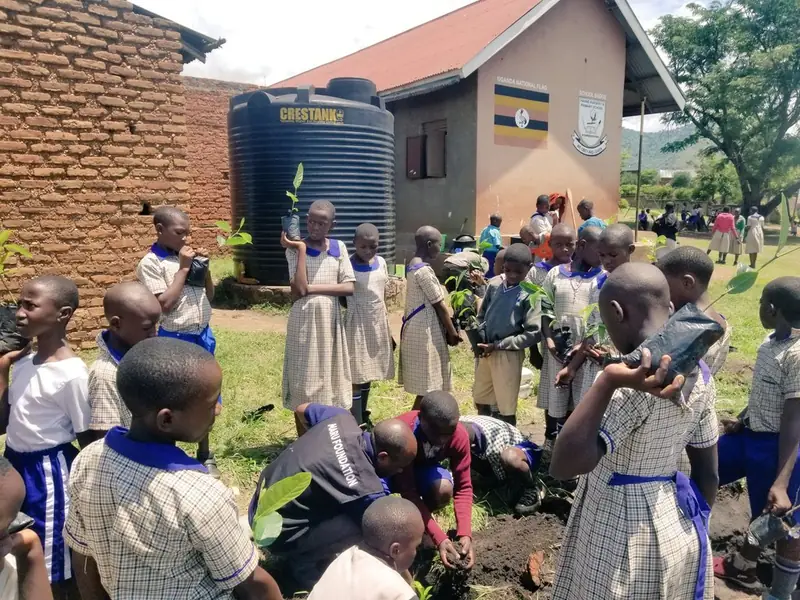 Pupils gather in a school compound next to a water tank