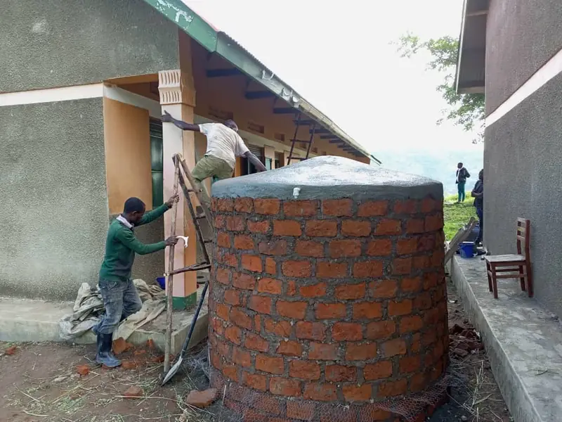 A brick rainwater storage tank under construction beside a school building