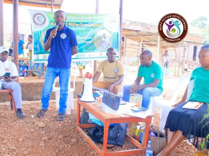 A man speaks into a microphone at an outdoor community meeting