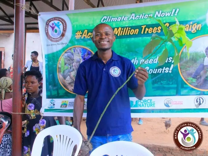 A young man presents in front of the Action 2 Million Trees Campaign banner
