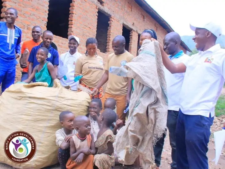 Volunteers sort donated sacks and clothing with children watching