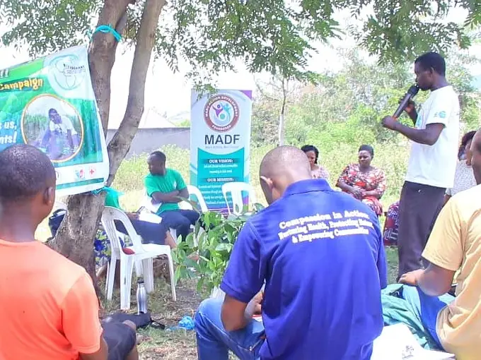 A speaker uses a microphone at an outdoor community workshop