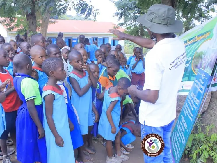 Pupils gather around a facilitator presenting a banner outdoors