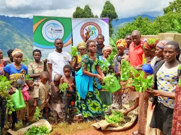Women hold up leafy vegetables beside Maru Foundation banners