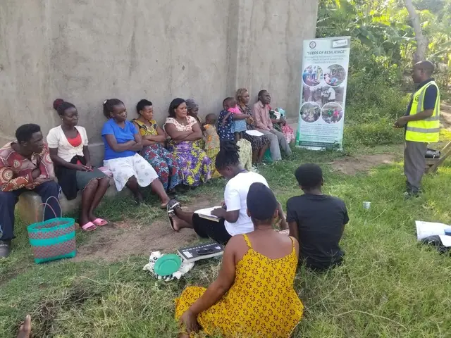 Participants sit on the grass and listen during an outdoor training